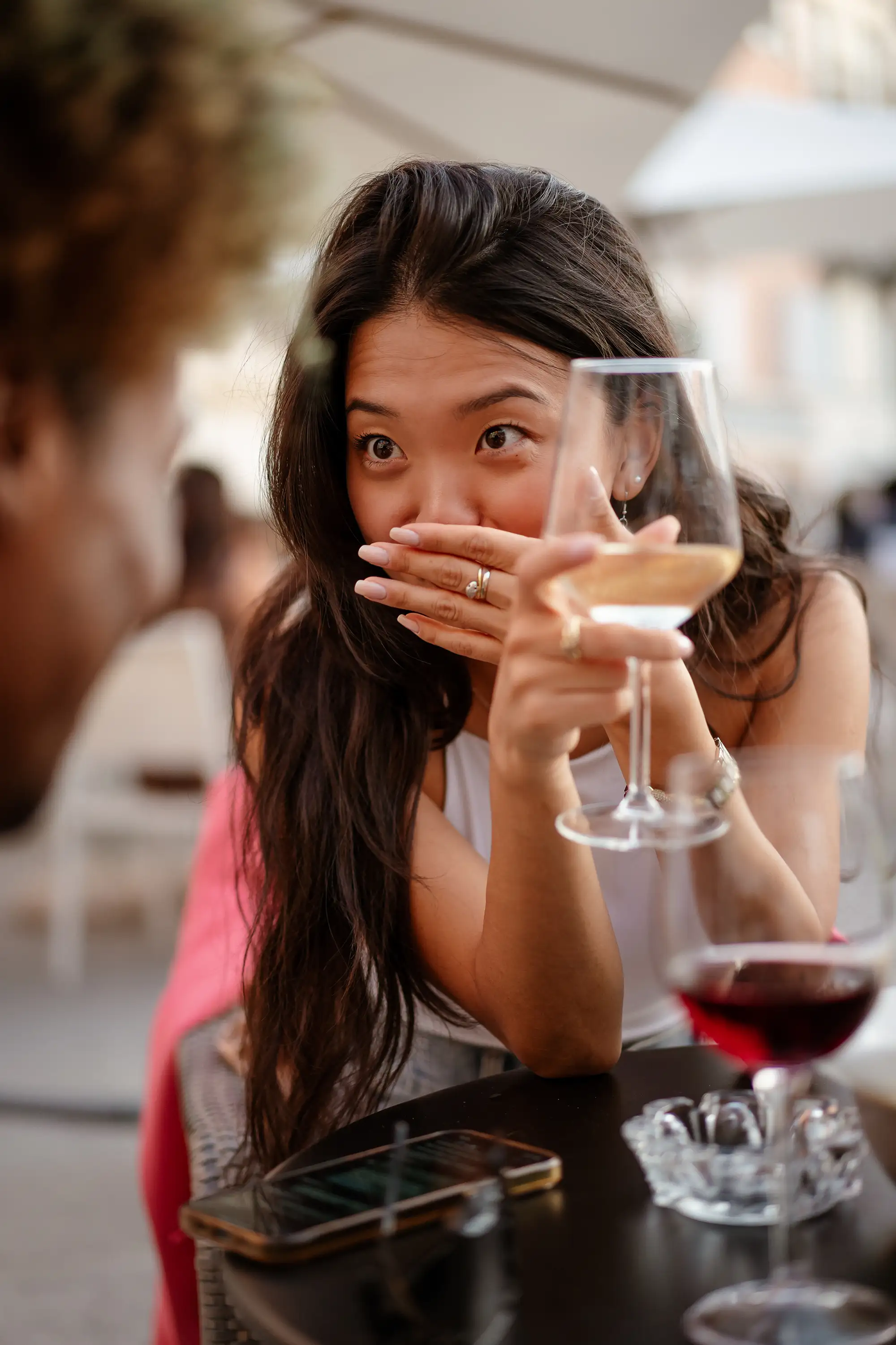 Young woman laughing while holding a wine glass during a relaxed social gathering