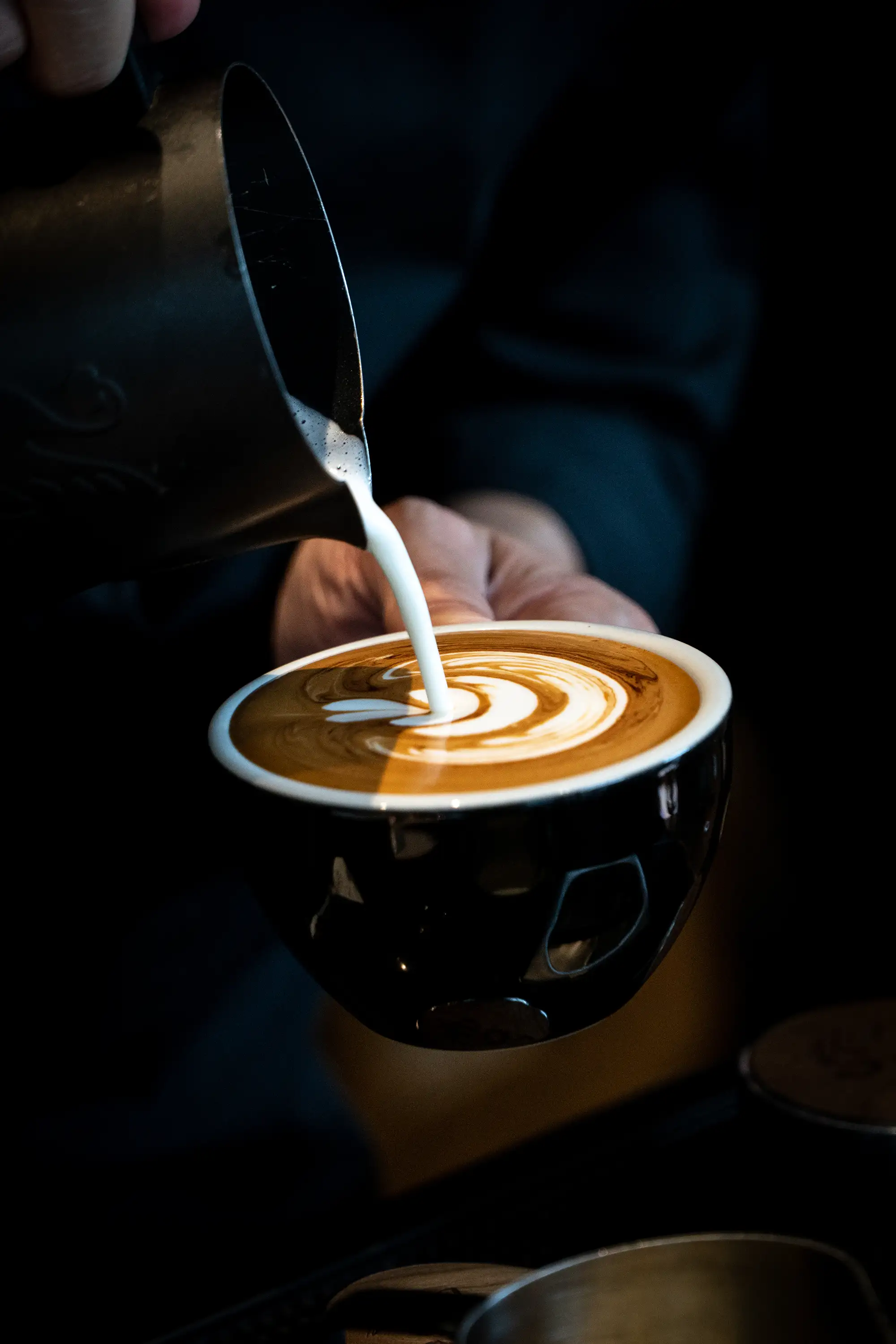 Close-up of coffee being poured into a ceramic cup in a café environment